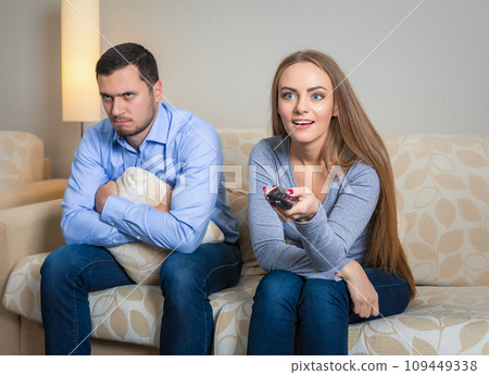 Portrait of couple sitting on sofa watching television. Portrait of couple sitting on sofa watching television. 109449338