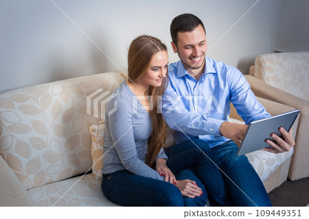 Young man and woman on the couch with electronic tablet Young man and woman on the couch with electronic tablet 109449351
