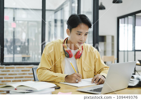 Young collage student using computer and mobile device studying online... 109449376