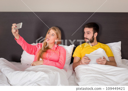 Young happy couple on bed doing selfie with telephone camera. 109449421
