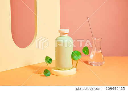 On a pink background, a green cosmetic on round podium with fresh gotu kola leaves decorated. Creative background for advertising cosmetic, natural ingredient for skin care On a pink background, a green cosmetic on round podium with fresh gotu kola leaves decorated. Creative background for advertising cosmetic, natural ingredient for skin care 109449425