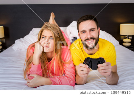 Young couple having playing videogames in bed Young couple having playing videogames in bed 109449515