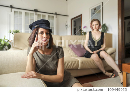 Two beautiful luxurious women sitting on a couch Two beautiful luxurious women sitting on a couch 109449953