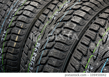 Studded new winter tires background, snow tires with metal studs Studded new winter tires background, snow tires with metal studs 109450842