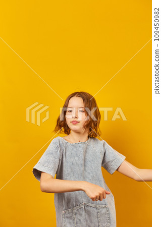 Happy teen girl dancing on yellow studio background 109450982