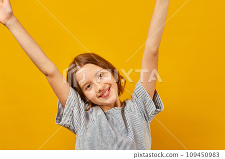 Happy teen girl dancing on yellow studio background 109450983