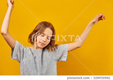 Happy teen girl dancing on yellow studio background 109450992
