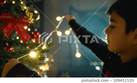 Kid Lighting a Christmas tree for holidays Kid Lighting a Christmas tree for holidays 109451520