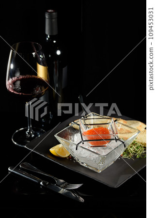salmon fish caviar, on ice, with croutons, lemon, on a transparent dish, on a dark background salmon fish caviar, on ice, with croutons, lemon, on a transparent dish, on a dark background 109453031