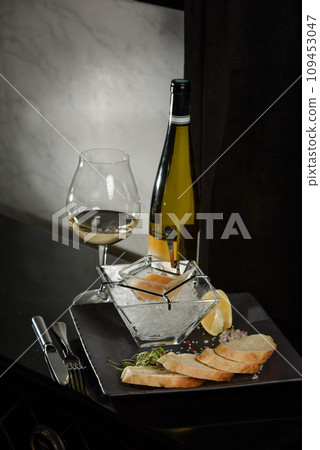 Pike fish caviar, on ice, with croutons, lemon, on a transparent dish, on a dark background 109453047