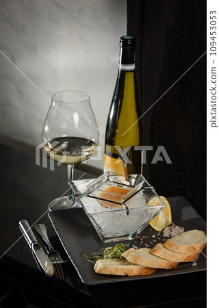 Pike fish caviar, on ice, with croutons, lemon, on a transparent dish, on a dark background 109453053