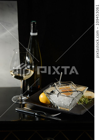 Pike fish caviar, on ice, with croutons, lemon, on a transparent dish, on a dark background 109453061