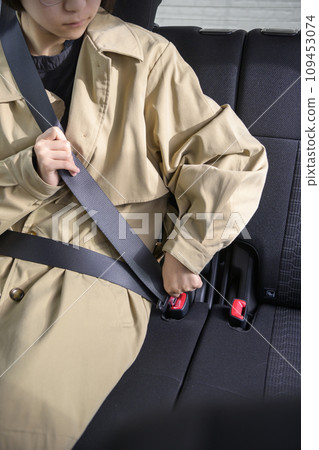 A person wearing a seatbelt in the back seat A person wearing a seatbelt in the back seat 109453074