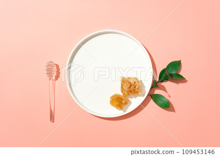 Top view of a ceramic dish with beeswax placed on, decorated with a honey dripping and some leaves. Honey is a natural antiseptic and anti-inflammatory  109453146