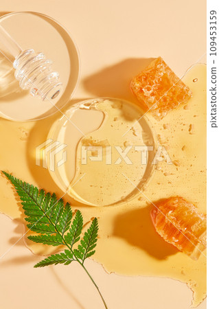 Glass podium arranged with a honey dripping and beeswax on honey. Stage showcase on pedestal display with beige background Glass podium arranged with a honey dripping and beeswax on honey. Stage showcase on pedestal display with beige background 109453159