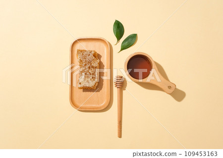 Fresh beeswax displayed on a wooden dish, decorated with a honey dripping and a bowl of honey. The antioxidants in honey help lower blood pressure 109453163