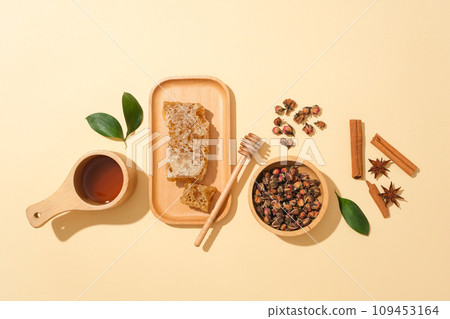 Wooden dish of beeswax arranged with a honey dripping, Cinnamon, star anise, bowls of honey and dried flowers. Commercial photo for branding advertising 109453164