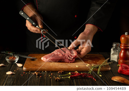 The process of preparing a meat steak by the hands of a chef on a kitchen table with aromatic spices. Cooking juicy and flavorful shish kebab for lunch or dinner 109454489