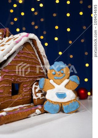 Christmas gingerbread in the shape of man is decorated with colorful sugar icing and a cookie house. Christmas gingerbread in the shape of man is decorated with colorful sugar icing and a cookie house. 109454695