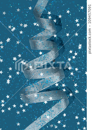 Silver party streamer in the shape of Christmas tree and sparkling star shape confetti on blue background. Holiday concept. Copy space. 109457091