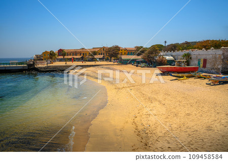 Sandy beach on Goree Island with colorful buildings and boats 109458584