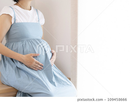 Belly of a pregnant woman sitting on a chair 109458666