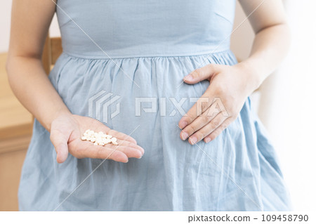 Image of a pregnant woman taking medicine 109458790