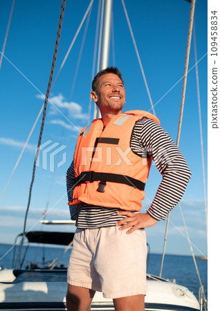Mature man in a life jacket on a yach feeling good 109458834