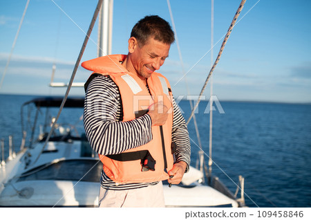 Man on a yacht putting on a life jacket 109458846