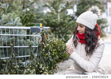 A young woman looks at mistletoe at the market during Advent A young woman looks at mistletoe at the market during Advent 109459024