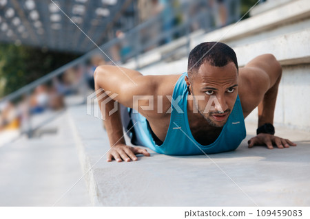 Man in blue tshirt exercising and doing push ups 109459083