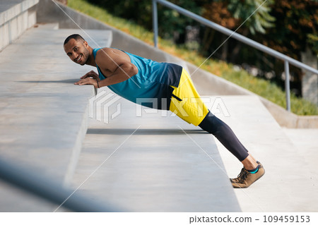 Good-looking dark-skinned athlete exercising on the stairs Good-looking dark-skinned athlete exercising on the stairs 109459153