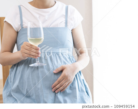 Pregnant woman holding a wine glass filled with wine 109459154