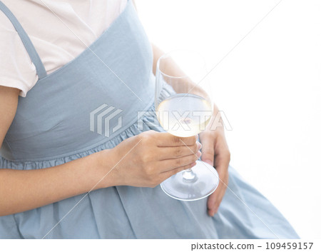 Pregnant woman holding a wine glass filled with wine 109459157
