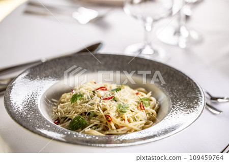 Italian Spaghetti Algio e Olio with Garlic Parmesan and chili peppers on restaurant festive table Italian Spaghetti Algio e Olio with Garlic Parmesan and chili peppers on restaurant festive table 109459764