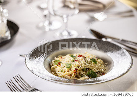 Italian Spaghetti Algio e Olio with Garlic Parmesan and chili peppers on restaurant festive table Italian Spaghetti Algio e Olio with Garlic Parmesan and chili peppers on restaurant festive table 109459765