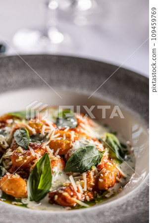 Gnocchi pomodoro with mascarpone, cream, basil and parmesan, in a stylish plate on a restaurant table Gnocchi pomodoro with mascarpone, cream, basil and parmesan, in a stylish plate on a restaurant table 109459769