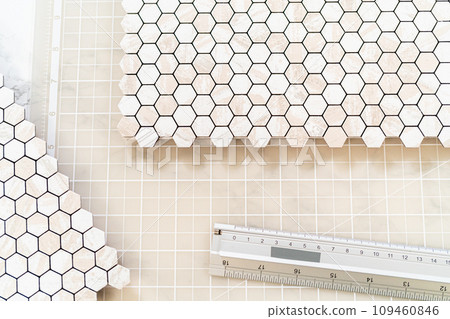 In the process of mounting peel and stick mosaic tiles onto a foam board, perfect for enhancing a food photography studio's aesthetic. 109460846