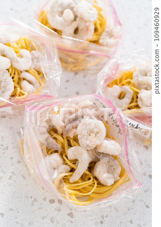 Packaging homemade frozen shrimp scampi meal prep into plastic resealable bags. Packaging homemade frozen shrimp scampi meal prep into plastic resealable bags. 109460929