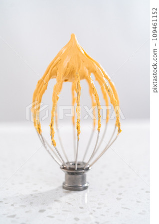 Freshly whipped dulce de leche buttercream frosting on a whisk. Freshly whipped dulce de leche buttercream frosting on a whisk. 109461152