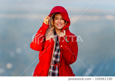 Close up beautiful Caucasian woman stand near cliff with hold coat hood and stay on the mountain with warm light of sun rise and she look happiness with smiling also look at camera. Close up beautiful Caucasian woman stand near cliff with hold coat hood and stay on the mountain with warm light of sun rise and she look happiness with smiling also look at camera. 109461190