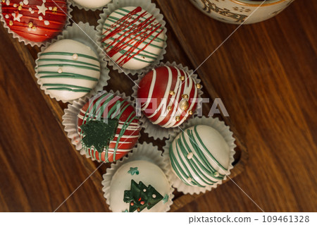 Rum balls of different colors decorated with chocolate in the shape of Christmas tree decorations Rum balls of different colors decorated with chocolate in the shape of Christmas tree decorations 109461328