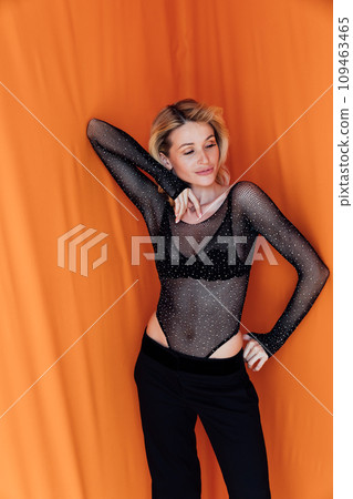 Beautiful blonde woman in black suit on orange background 109463465