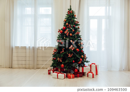 Christmas tree with red gifts in the interior of a room with windows Christmas tree with red gifts in the interior of a room with windows 109463500