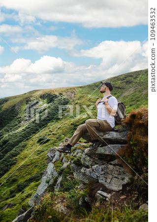 Man in the mountains sitting on a rock 109463532