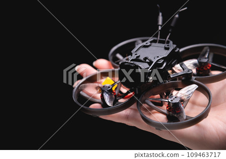 Hands holding a racing drone with a camera. Woman holding a radio-controlled mini quadcopter Hands holding a racing drone with a camera. Woman holding a radio-controlled mini quadcopter 109463717