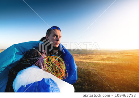 guy holds the lines of a paraglider in his hands close-up. A male paraglider carries a paraglider to a pasture. The pilot checks the paraglider's lines to ensure they are not damaged. 109463758