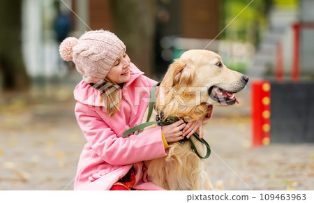 Preteen girl kid with golden retriever dog sitting in the park and hugging doggy. Female child with pet at autumn Preteen girl kid with golden retriever dog sitting in the park and hugging doggy. Female child with pet at autumn 109463963