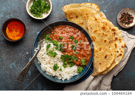 Traditional Indian Punjabi dish Dal makhani with lentils and beans in black bowl served with basmati rice, naan flat bread, fresh cilantro and spoon on blue concrete rustic table top view Traditional Indian Punjabi dish Dal makhani with lentils and beans in black bowl served with basmati rice, naan flat bread, fresh cilantro and spoon on blue concrete rustic table top view 109464184