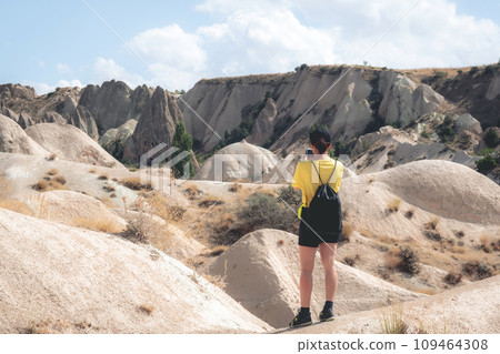 Woman standing backwards while photographing landscape in Cappadocia, Turkey 109464308